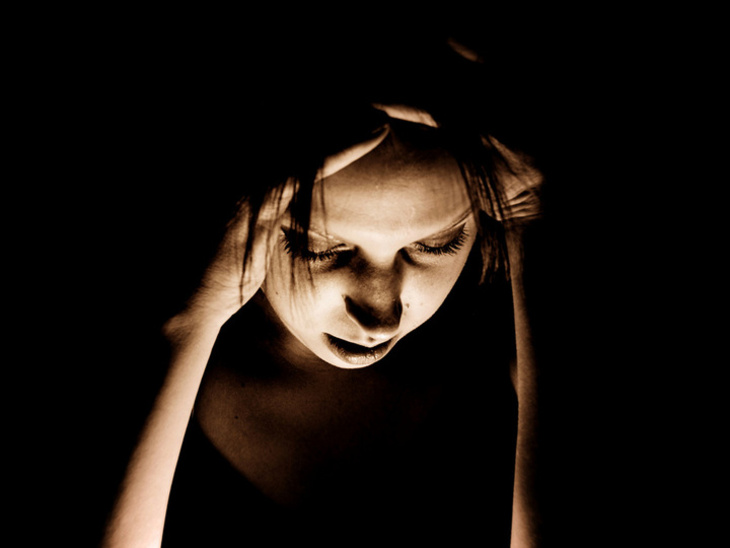 Junge frau greift sich mit den Händen an den Kopf um sich zu konzentrieren