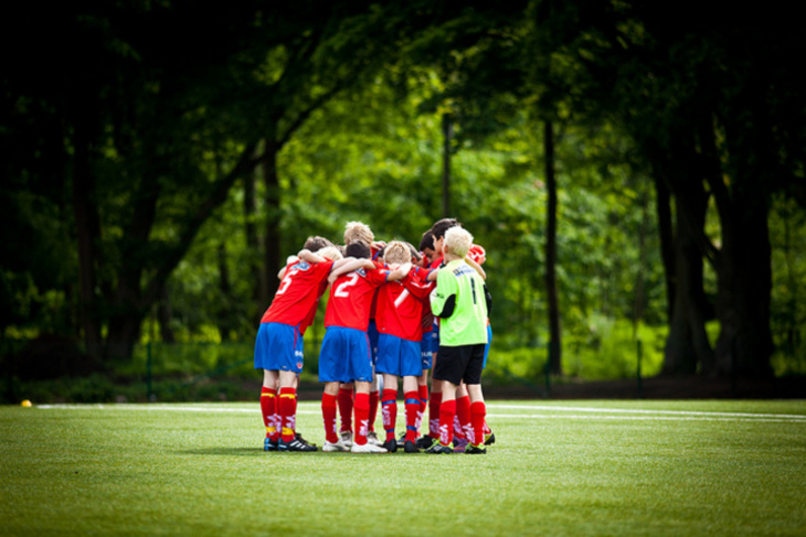 Einige Kinder in Fußballtrikots stehen auf dem Rasen und bilden einen Kreis